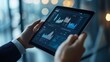 © Monchisa - Young entrepreneur engaged with data dashboard graphs on a tablet, modern office setting, showcasing innovation and analytical skills in a professional atmosphere