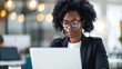 © LukaszDesign - Professional woman using a laptop with glasses while reading or writing an email in an office setting. Smiling entrepreneur at her desk with technology and blurred background for work and analysis