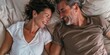 © LukaszDesign - Mature couple enjoying quality time on a bed in their stylish apartment. They are happily bonding and conversing during a romantic getaway