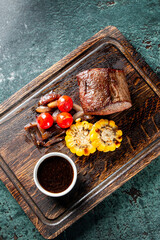 Wall Mural - Top view of a grilled steak on a wooden board with roasted vegetables and sauce. Perfect for culinary themes, showcasing delicious, well-prepared food