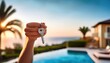 © Juri_Tichonow - A person holding a key in front of a luxurious poolside home during sunset.