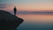 © Chexy139 - A person stands quietly on the edge of a tranquil lake during sunset, reflecting on the calm waters and beautiful sky