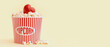 © Pixel-Shot - Bucket of popcorn and heart on yellow background. Valentine's Day celebration