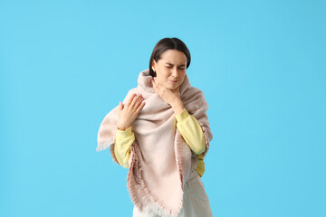 Poster - Young woman in scarf suffering from sore throat on blue background