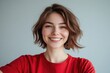 © Vii - A happy woman wearing a bright red shirt and smiling directly at the camera