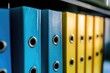 © Vii - A row of blue and yellow binders organized on a shelf, ready for use