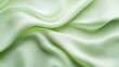 © setiadio - A close-up of smooth, flowing light green fabric, showcasing its texture and sheen.