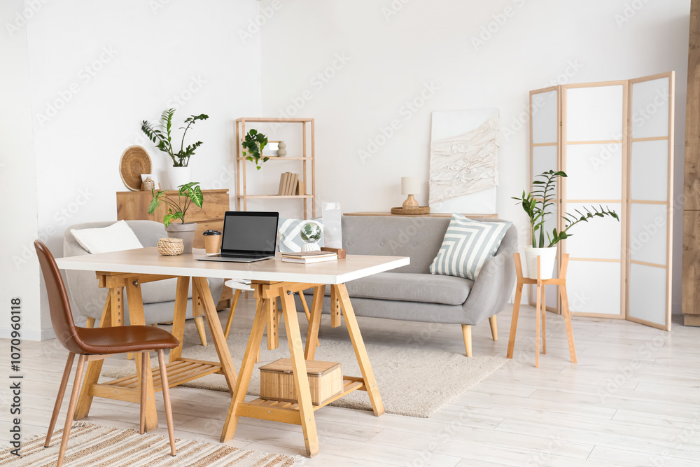 Interior of light living room with programmer's workplace, sofa and armchair