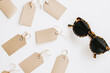 © tynza - Minimalist flat lay of sale tags and discount coupons scattered on a white surface, with a stylish pair of sunglasses.
