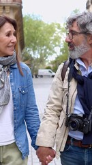 Wall Mural - Vertical HD video. Happy senior couple of tourist walking in the city street. Attractive mature people talking while sightseeing Barcelona. Retirement lifestyle and vacation concept.