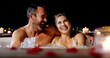 © peopleimages.com - Happy couple, night and relax with jacuzzi for honeymoon vacation, holiday or date together at luxury resort. Man, woman or lovers enjoying water with hot tub in late evening for romance or getaway