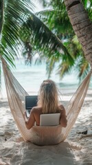 Wall Mural - A woman working on laptop computer while relaxing in beach hammock