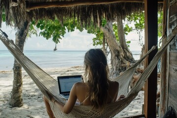 Wall Mural - A woman working on laptop computer while relaxing in beach hammock