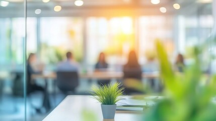 Poster - A small potted plant sits on a table in a modern office, with a group of people in the background.
