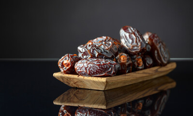 Dates in wooden dish on a black background.