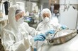 © Seventyfour - Medium shot of female process technician in protective coverall suit opening tank lid while controlling product fermentation with colleague in factory workshop, copy space