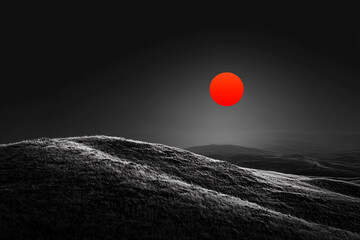 Wall Mural - Red sun setting over rolling hills in a monochrome landscape