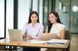 © junjira - Businessman, two Asian women give advice, discuss work, documents on laptop at office