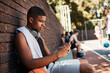 © peopleimages.com - Court, basketball player and man with smartphone for online, connection and watch video on social media. Sports, male person and athlete with mobile app for fitness tips, advice and scroll outdoor
