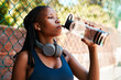 © peopleimages.com - Fitness, court and black woman with water for drinking, hydration and break for basketball competition. Fence, female person and athlete with rest for liquid beverage, sports game and h2o for thirst