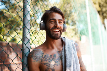 Wall Mural - Man, outdoor and towel in portrait for fitness or training on basketball court as athlete. Male person, headphones and music on fence for competition, exercise or game with listening or streaming