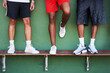 © peopleimages.com - Sports, basketball and legs of people on bench by wall on court for match, fitness exercise and training. Green background, athletes or players with shoes or sneakers for footwear, workout or game