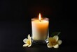 © Iqra - A lit candle in a glass jar with a flower next to it, against a black background