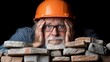 © Anna - An older man with glasses and a hard hat shows signs of concern while examining a stack of bricks. The low lighting emphasizes his expression, highlighting the stress of his construction task