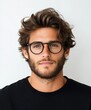 © Odin AI - A confident young man with thick curly hair and round glasses wearing a black shirt, posing in front of a plain background with calm expression.