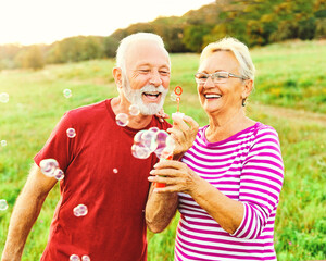 Wall Mural - woman man outdoor senior couple happy fun retirement together bubble soap blowing love old nature ma