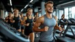 © imagineRbc - A man is running on a treadmill with a group of people behind him. The man is smiling and he is enjoying himself. The group of people are also running