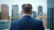 © Riko - Back view of a mature businessman in a suit overlooking city skyline. Leadership and corporate concept