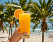 © amnat - A person holding a glass of orange juice on the beach.