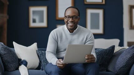 Poster - A man is sitting on a couch holding a laptop