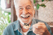 © luciano - Close up portrait of happy bearded senior man eating a fruit cake in coffee shop enjoying break or breakfast and looking at camera
