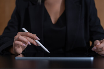 Poster - woman's hands holding a stylus over a digital tablet. dark background. concept of modern technology 