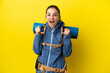 © luismolinero - Young mountaineer woman with a big backpack over isolated yellow background celebrating a victory in winner position