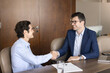 © fizkes - Happy successful male business partners shaking hands after negotiation, consultation meeting at workplace table, smiling, laughing, discussing partnership, getting agreement