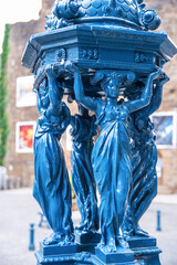 Wall Mural - A blue Wallace fountain in a street in the town of Villedieu-les-Poêles in Normandy in France