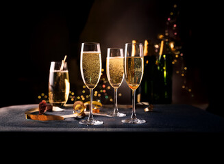 Aufkleber - Three champagne flutes filled with sparkling wine sit on a dark table, with bottles of champagne in the background.