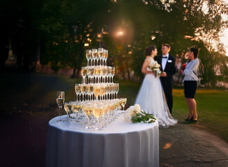 Poster - A wedding reception with a champagne pyramid and a bride and groom talking to a guest.
