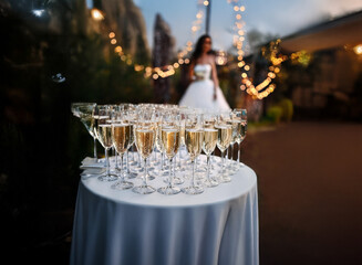 Poster - A table with champagne flutes filled with sparkling wine for guests at an outdoor wedding reception.