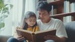 © Gulnaz - A man and a little girl are sitting on a couch reading a book together