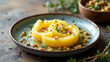 © Tameem - Sliced golden potatoes cooked to perfection in a pot filled with beef fat, topped with chopped herbs and nuts for added texture and flavor.