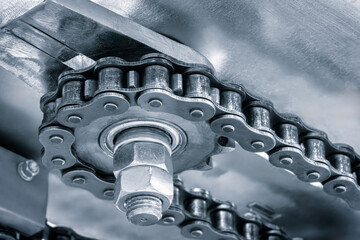 Aufkleber - A chain with a nut on it. The chain is silver and has many small holes. The chain is attached to a machine