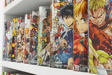 Colorful manga graphic novels on a bookshelf.