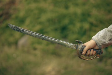 A naval broadsword.A child's hand with a plastic saber.A game of sailors and pirates.