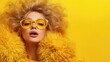 © svastix - A fashionable woman poses confidently in a yellow fur coat against a matching backdrop. The image radiates style, elegance, and a bold fashion statement.