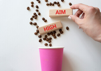 Aim High symbol. Concept word Aim High on wooden blocks. Beautiful white background with coffee cup. Businessman hand. Business and Aim High concept. Copy space