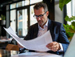 © koala studio - Focused businessman reading contract in cafe
